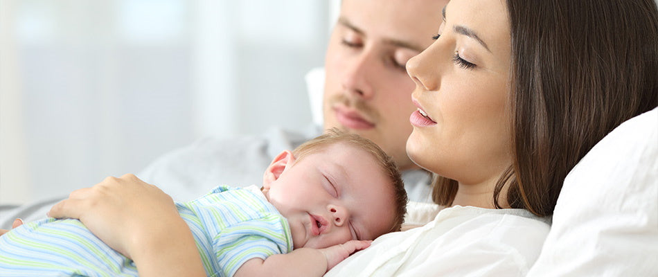 Ein Paar schläft gemeinsam mit ihrem neugeborenen Baby auf der Brust der Mutter.